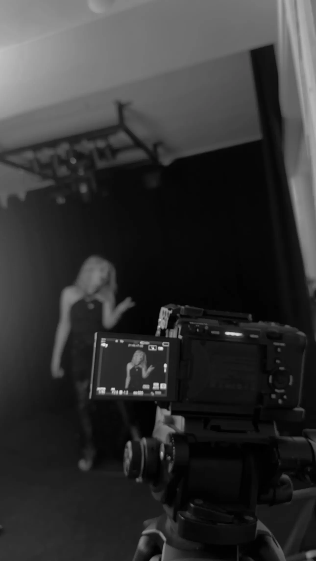 Behind the camera on a music video shoot, the artist performing on a darkened stage