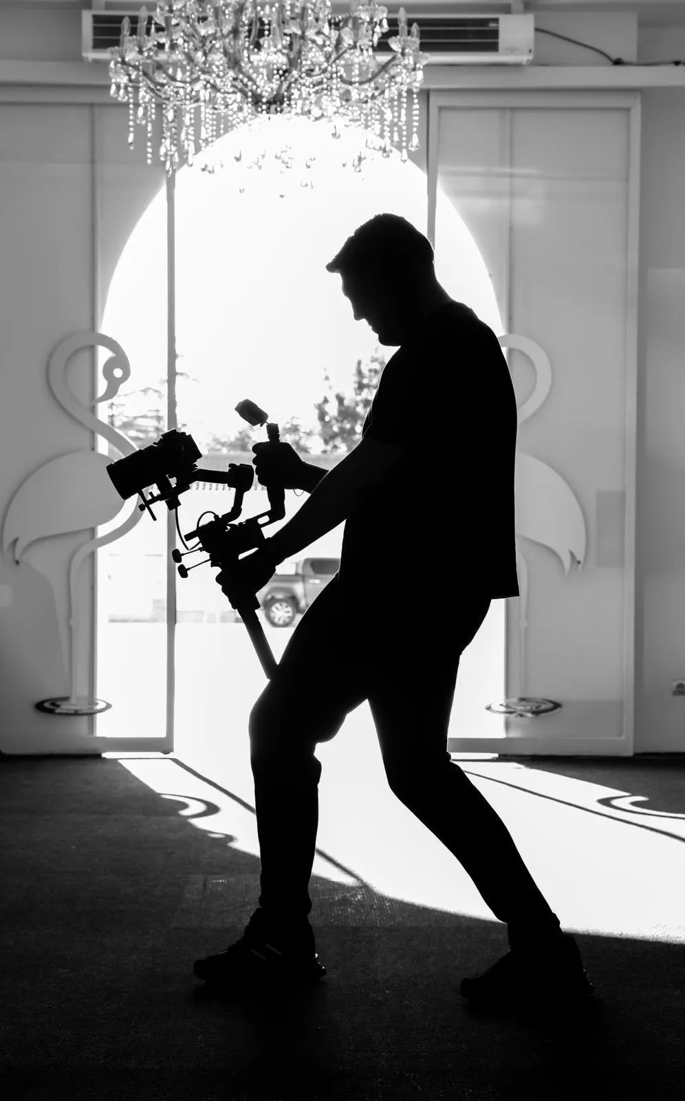 Gimbal ile çekim yapan operatör, aydınlık bir kapının önünde siluet halinde