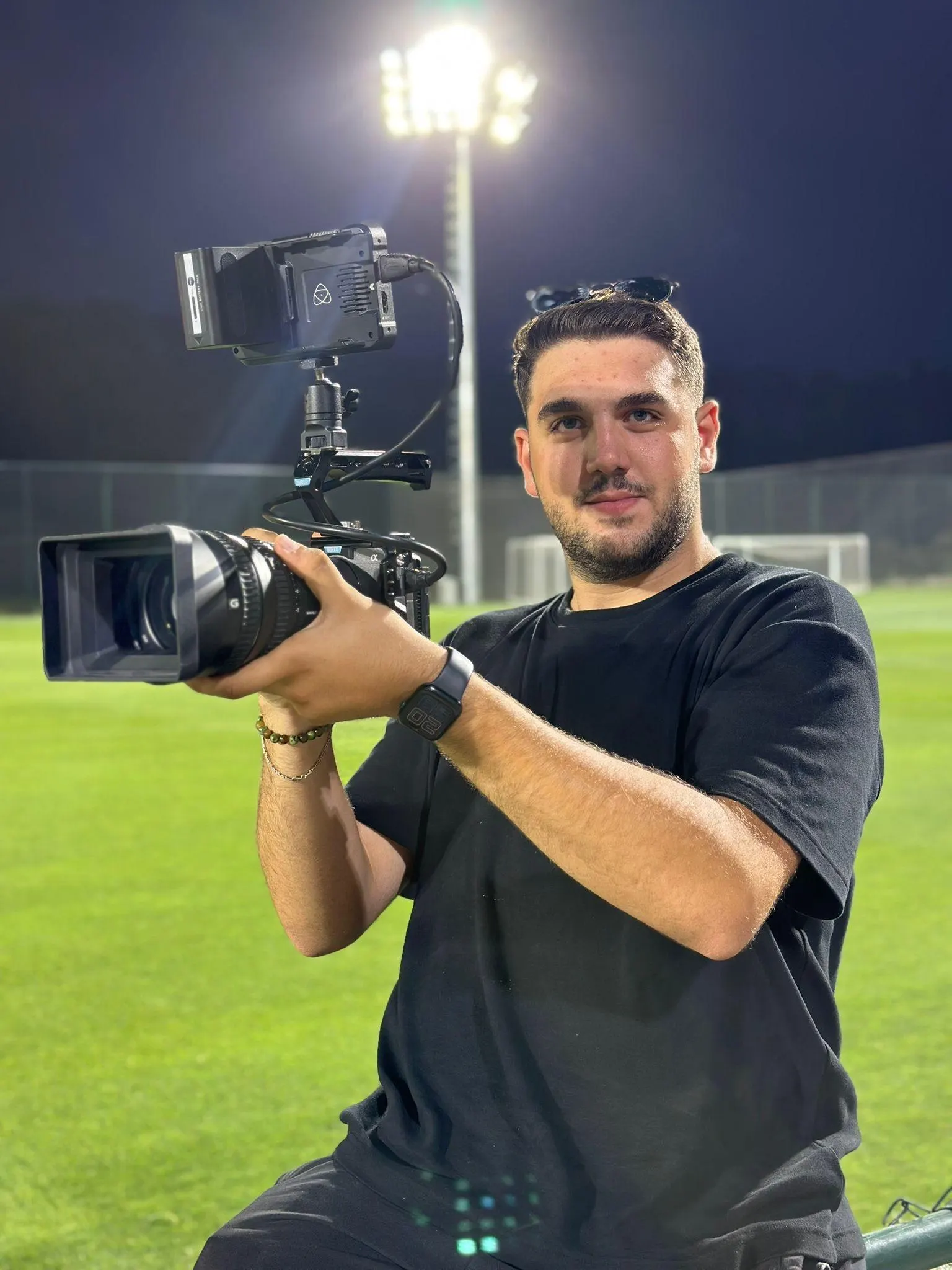 Furkan Kayanoğlu shooting with a shoulder-mounted camera on a pitch at night